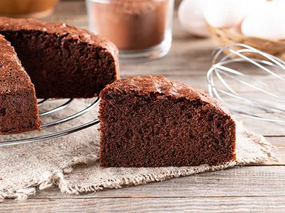 Piece of delicious fresh homemade chocolate sponge cake on wooden table